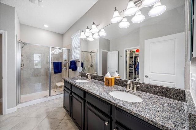 bathroom with a stall shower, a walk in closet, double vanity, and tile patterned flooring