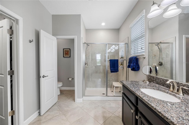 bathroom with a stall shower, toilet, vanity, and tile patterned floors