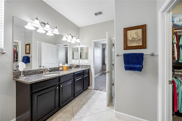 bathroom featuring double vanity, tile patterned flooring, a walk in closet, and baseboards