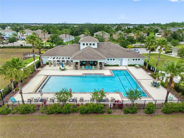 community pool featuring fence, a patio area, and a residential view