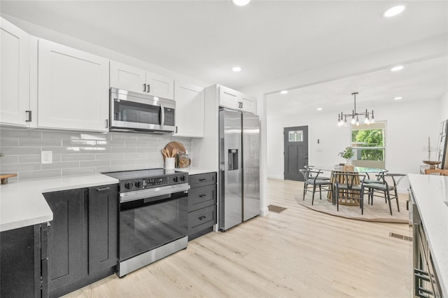 7 Hamilton Heath Dr, Tampa, FL 33604 - kitchen with stainless steel appliances, white cabinets, light countertops, decorative backsplash, and light wood finished floors
