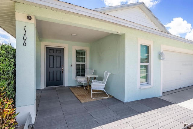 property entrance featuring a garage and stucco siding