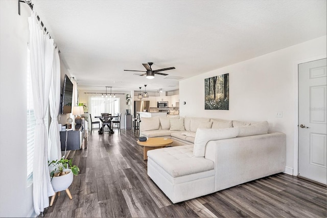 living room featuring ceiling fan, dark wood-style flooring, and a chandelier