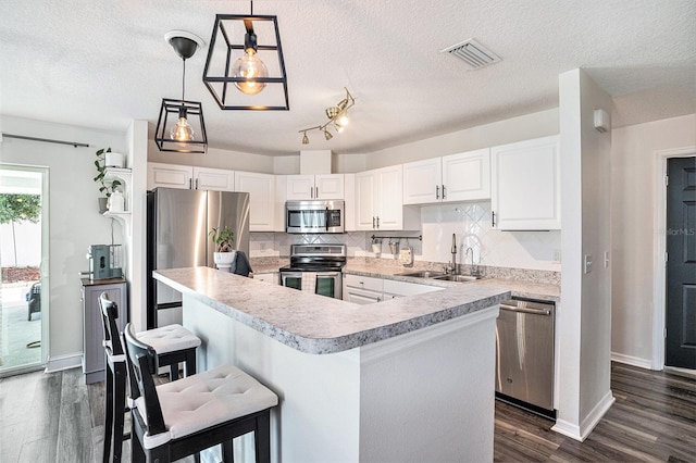 kitchen featuring stainless steel appliances, a sink, light countertops, decorative backsplash, and dark wood-style floors