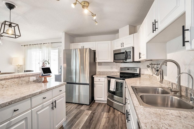 kitchen featuring appliances with stainless steel finishes, a sink, a textured ceiling, white cabinets, and dark wood-style floors