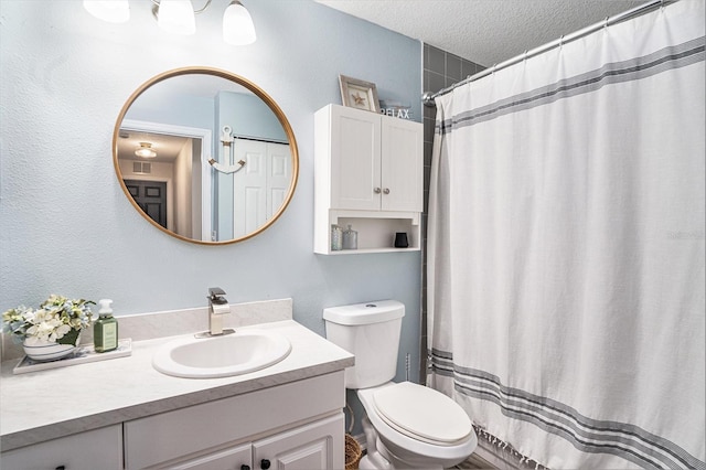 bathroom with a textured ceiling, vanity, toilet, and curtained shower