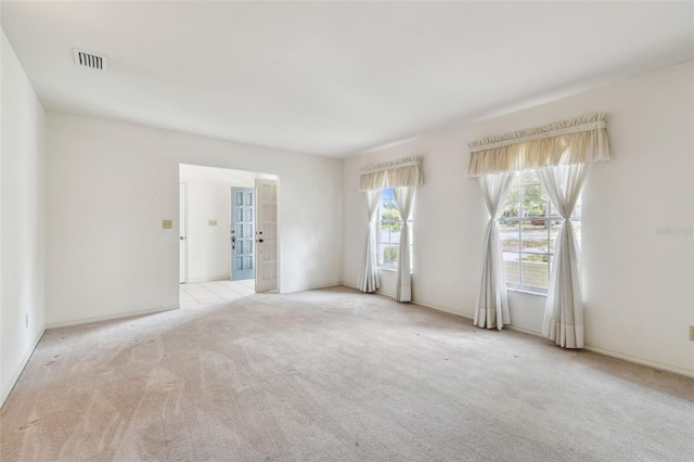 spare room featuring light carpet and baseboards