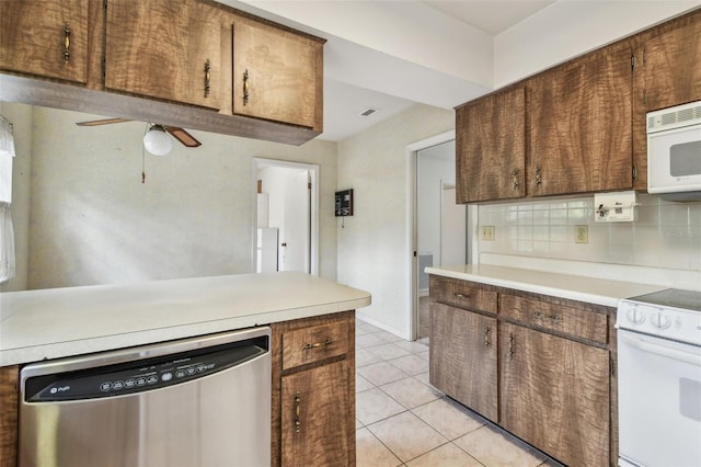 kitchen featuring white appliances, ceiling fan, light tile patterned flooring, light countertops, and decorative backsplash