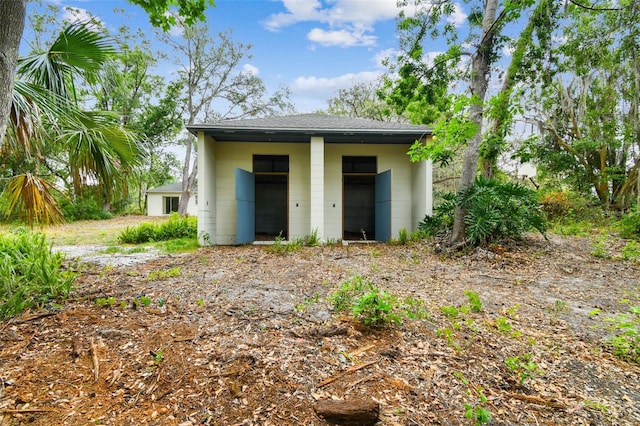 back of property with concrete block siding and a shingled roof