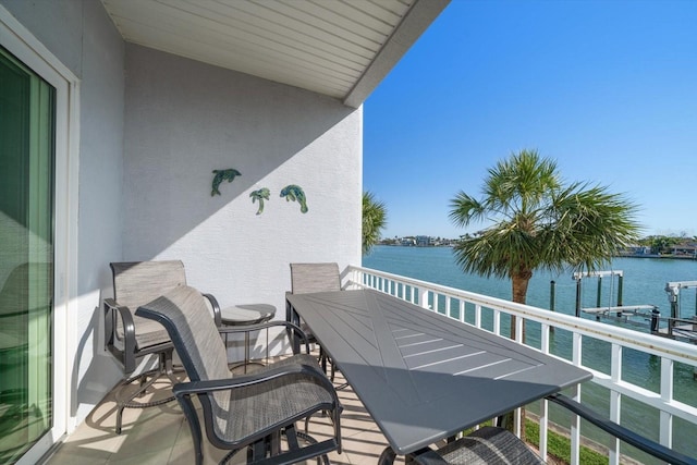 balcony with a water view and outdoor dining space