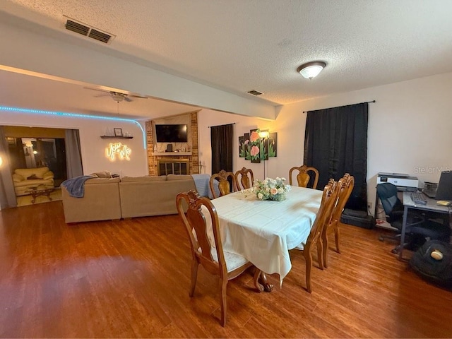35058 Whispering Oaks Blvd, Dade City, FL 33523 - dining area featuring a textured ceiling, wood finished floors, and a brick fireplace