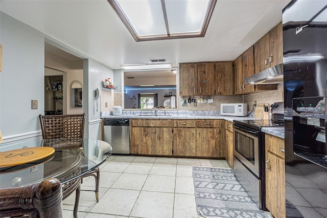 35058 Whispering Oaks Blvd, Dade City, FL 33523 - kitchen featuring appliances with stainless steel finishes, under cabinet range hood, a sink, light tile patterned floors, and backsplash