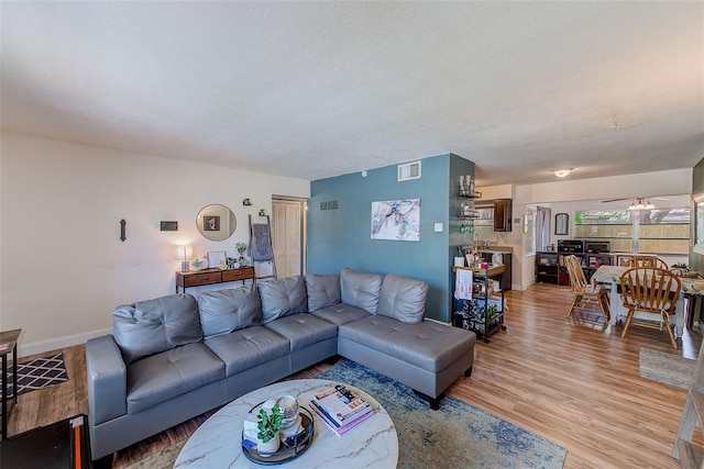 living room featuring a ceiling fan, light wood-style flooring, and baseboards