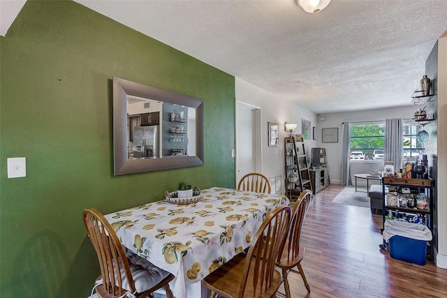 dining room with wood finished floors and a textured ceiling