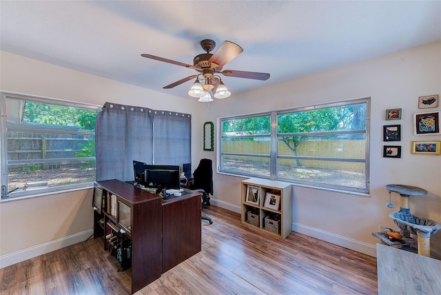 home office featuring a ceiling fan, healthy amount of natural light, baseboards, and wood finished floors