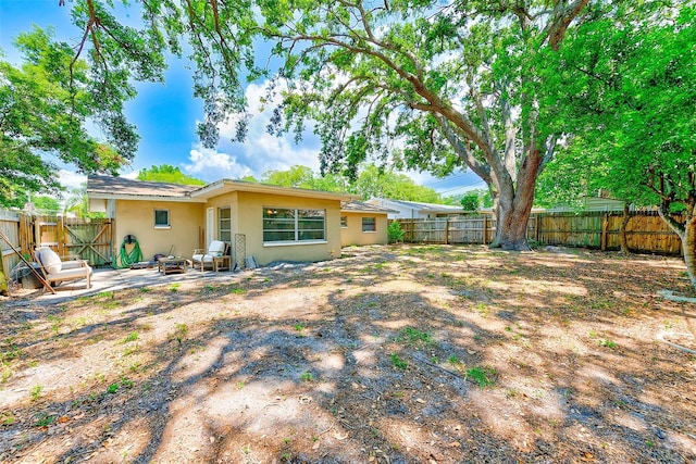 rear view of property with stucco siding, a fenced backyard, and a patio area