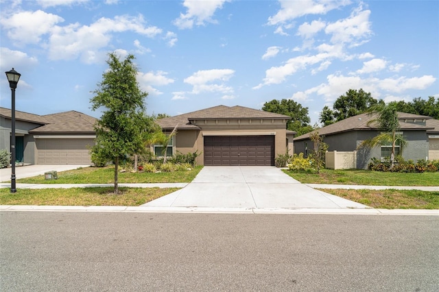 prairie-style house featuring driveway, a garage, a front yard, and stucco siding