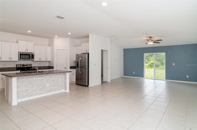 kitchen featuring appliances with stainless steel finishes, open floor plan, ceiling fan, a kitchen island with sink, and white cabinetry