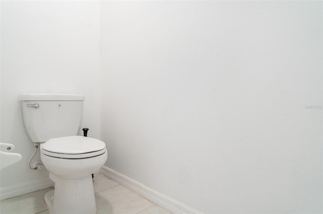 bathroom featuring baseboards, tile patterned floors, and toilet