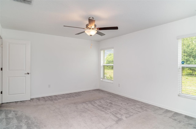 carpeted empty room with healthy amount of natural light, ceiling fan, and baseboards