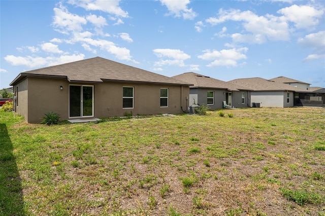 rear view of house with stucco siding and a lawn