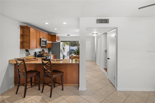 108 Biscayne Ave Unit B, Tampa, FL 33606 - kitchen featuring stainless steel appliances, open shelves, light stone countertops, brown cabinets, and recessed lighting