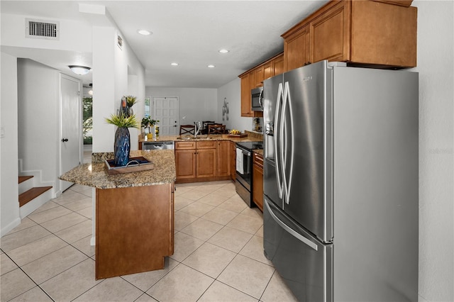 108 Biscayne Ave Unit B, Tampa, FL 33606 - kitchen with appliances with stainless steel finishes, a peninsula, a sink, brown cabinets, and stone countertops