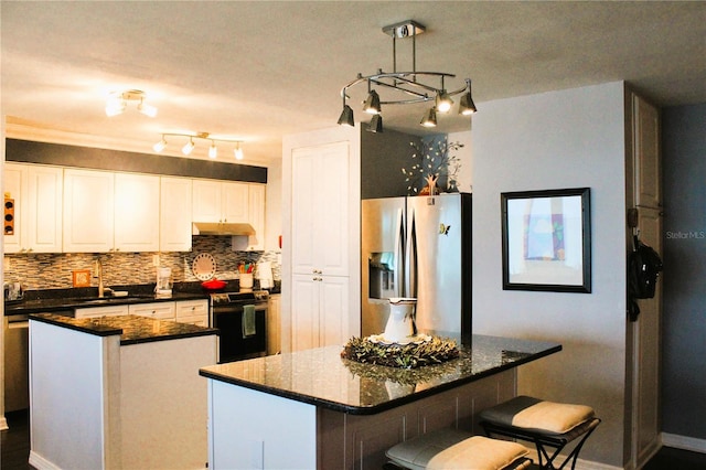 kitchen with stainless steel appliances, a kitchen island, a sink, tasteful backsplash, and white cabinetry