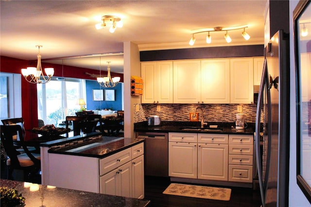 kitchen with a sink, a chandelier, dishwashing machine, white cabinets, and backsplash