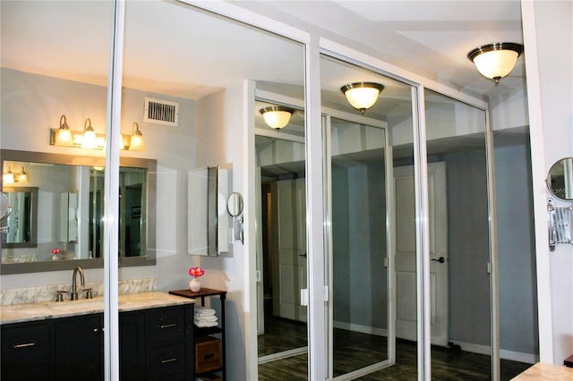 bathroom featuring vanity, wood finished floors, and baseboards