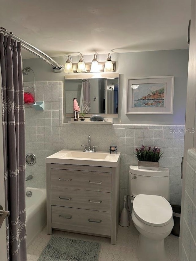 full bath with tile walls, toilet, shower / bath combo with shower curtain, vanity, and tile patterned flooring