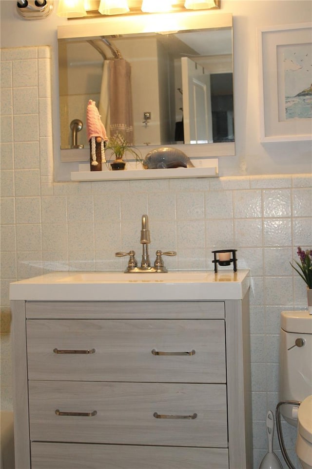 bathroom featuring vanity, tile walls, and toilet