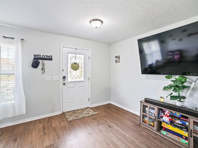 entryway with baseboards, wood finished floors, and a textured ceiling