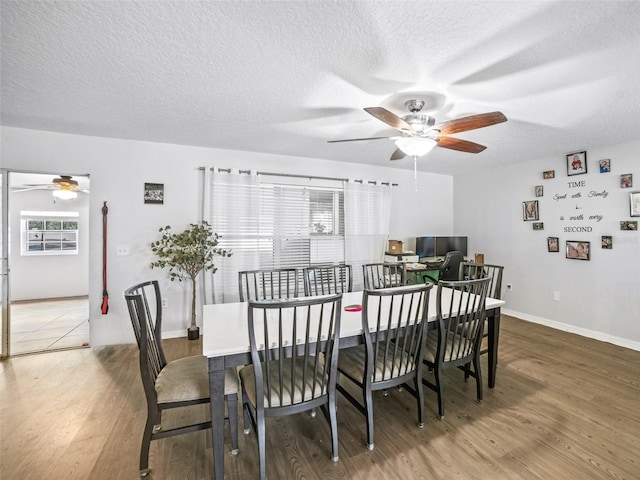 dining space with ceiling fan, wood finished floors, a textured ceiling, and baseboards