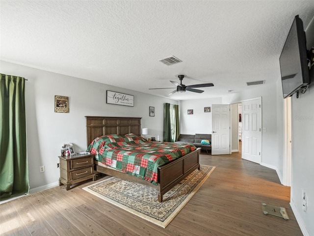 bedroom featuring wood finished floors, baseboards, a textured ceiling, and ceiling fan