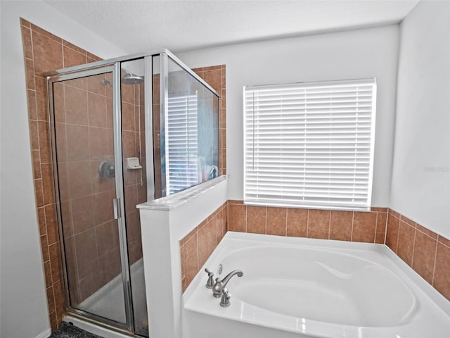 bathroom featuring a stall shower, a bath, and a textured ceiling