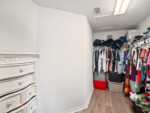 walk in closet with wood finished floors and attic access