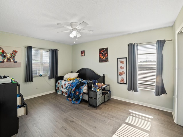 bedroom with wood finished floors, baseboards, and a ceiling fan