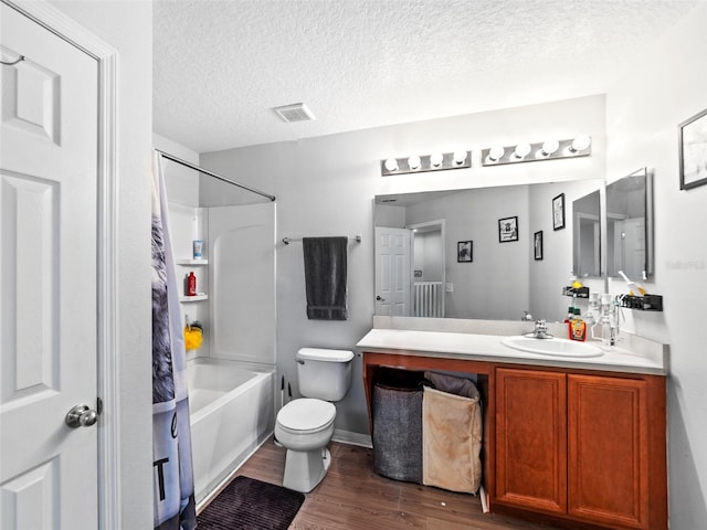 bathroom featuring wood finished floors, toilet, vanity, bathing tub / shower combination, and a textured ceiling
