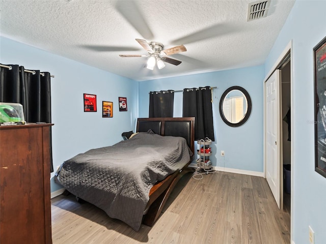 bedroom with wood finished floors, a textured ceiling, ceiling fan, a closet, and baseboards
