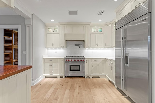 493 Lucerne Ave, Tampa, FL 33606 - kitchen featuring high end appliances, light wood-style floors, glass insert cabinets, backsplash, and wood counters