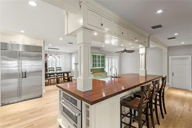 493 Lucerne Ave, Tampa, FL 33606 - kitchen featuring wooden counters, decorative columns, appliances with stainless steel finishes, light wood-style flooring, and a ceiling fan