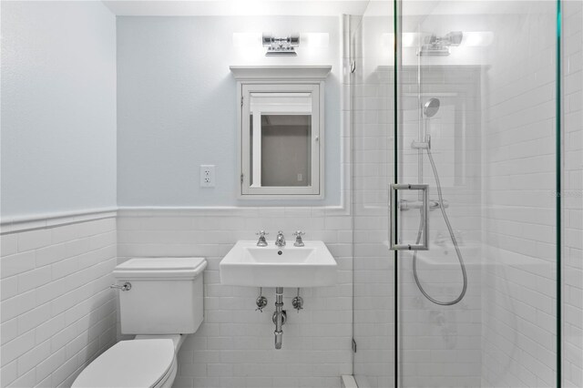 493 Lucerne Ave, Tampa, FL 33606 - bathroom featuring a stall shower, a sink, toilet, a wainscoted wall, and tile walls