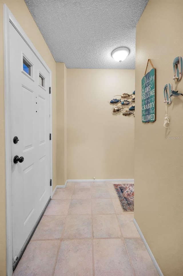 corridor featuring baseboards and a textured ceiling
