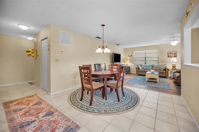 dining area with light tile patterned flooring, a chandelier, ceiling fan, and baseboards