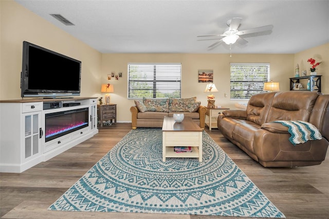 living area with a ceiling fan, wood finished floors, and baseboards
