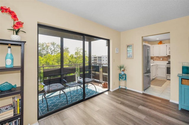 doorway featuring light wood-type flooring, baseboards, and a textured ceiling