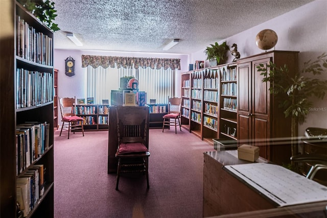sitting room featuring bookshelves, a textured ceiling, and carpet