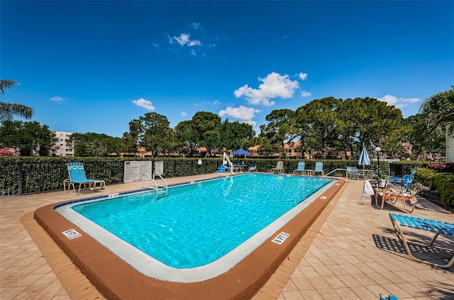 community pool with a patio and fence