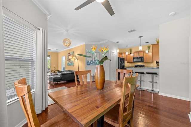 dining area with ceiling fan, hardwood / wood-style floors, ornamental molding, and baseboards